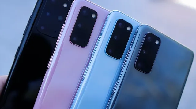 Four smartphones in blue pink black and grey against blurry background