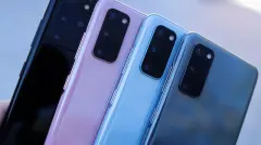 Four smartphones in blue pink black and grey against blurry background
