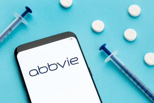 AbbVie Logo on white smartphone screen next to syringes and pills
