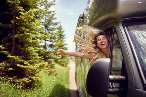 Happy lady hanging out window of RV with breeze in hair