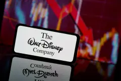 The Walt Disney company logo on smartphone with share price chart behind