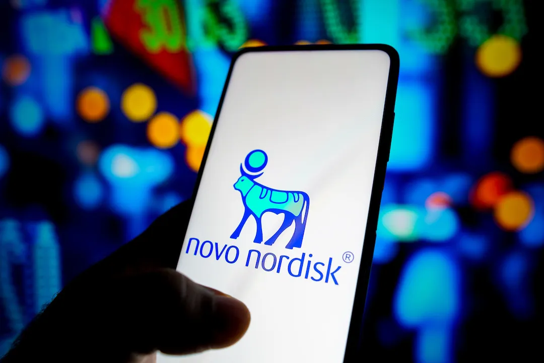 NVO stock NOVO Nordisk Logo on handset against stock chart