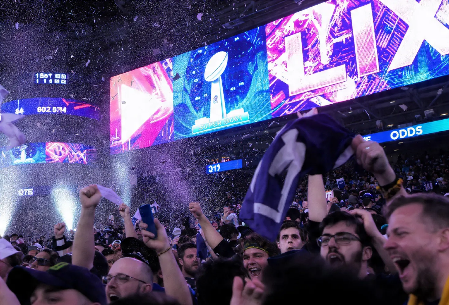 Crowd cheering at Super Bowl LIX night with crypto betting screens