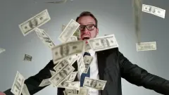 Dollar bills falling from the sky in front of man with wide-eyed open mouthed expression