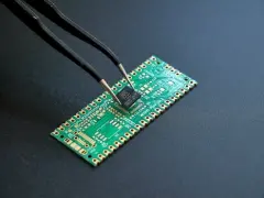 Semiconductor Chip adjusted and built with tweezer tool on black background