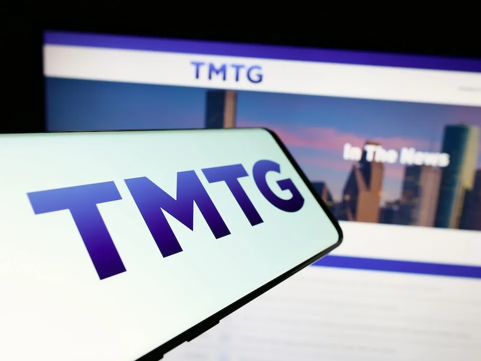 Mobile phone with logo of American company Trump Media Technology Group (TMTG) in front of business website. Focus on center of phone display.