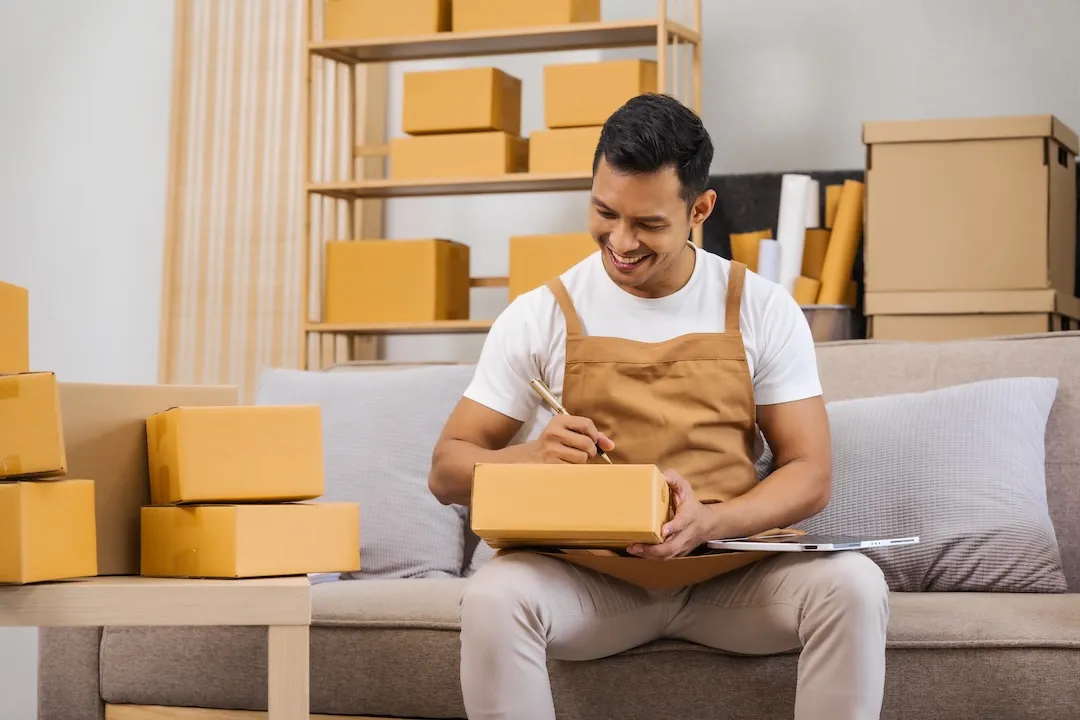 Men working from home, managing an online small business, sitting on the sofa, checking items, packing products, and preparing orders for shipment