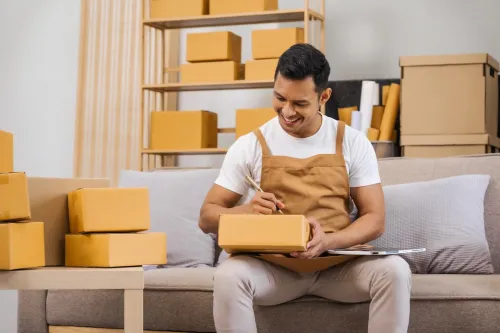 Men working from home, managing an online small business, sitting on the sofa, checking items, packing products, and preparing orders for shipment