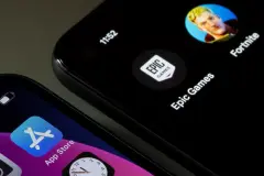 Alphabet vs Epic Games app icon on phone next to App Store icon on smartphone