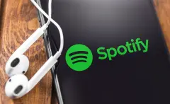 Spotify SPOT stock image logo on smartphone with headphones