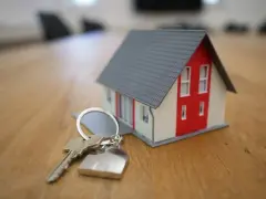 Keys and miniature house on wooden table