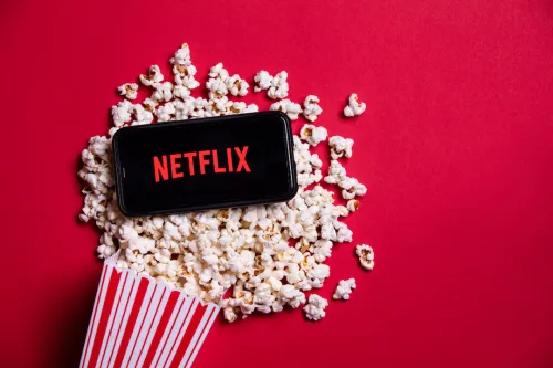 Netflix Logo on smartphone sitting in pool of popcorn pouring out of popcorn bucket
