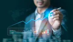 analyst drawing an upward arrow on a window with stock and volume price charts below