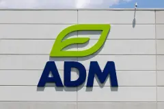 The image shows the ADM logo with a green leaf symbol above blue lettering, set against an exterior wall and clear sky.