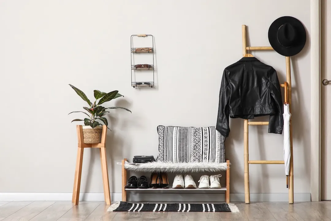Bench with stand for shoes and jacket hanging on ladder in interior of hallway