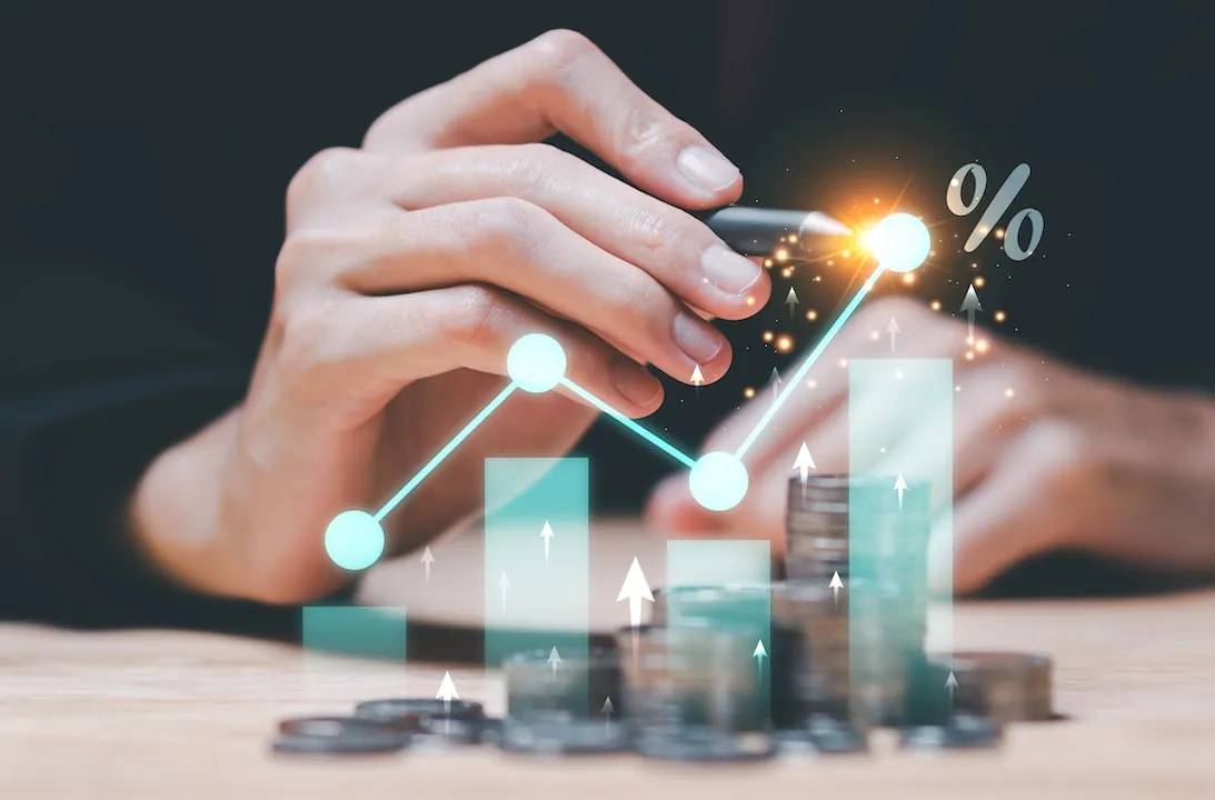 An Image of a hand depicting growth investing overlayed with a graphic barchart and graph against piles of coins.
