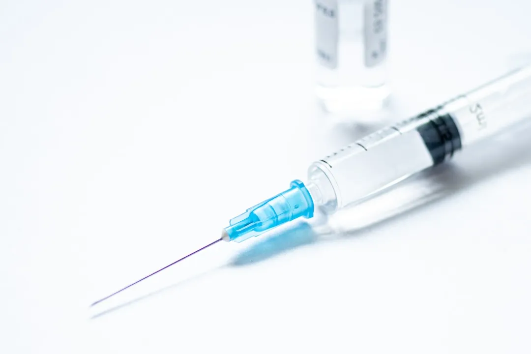 Syringe with needle without cover or top, vial or phial on a white empty space background ready to be used.