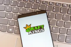 DraftKings logo on smartphone screen. Keyboard behind.