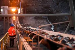 Shallow depth of field image of a miner inspecting ore rocks on a conveyor in NSW Australia