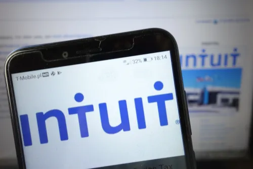 Intuit Logo on smartphone screen with Intuit website on screen in background.