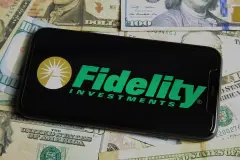 Fidelity Investments. Closeup of mobile phone with logo of fidelity investments, us dollar paper banknotes background