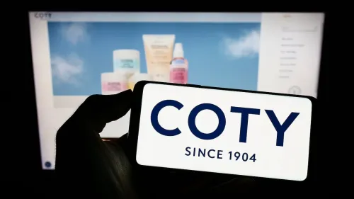 COTY Logo on smartphone screen with Coty cosmetics in background.
