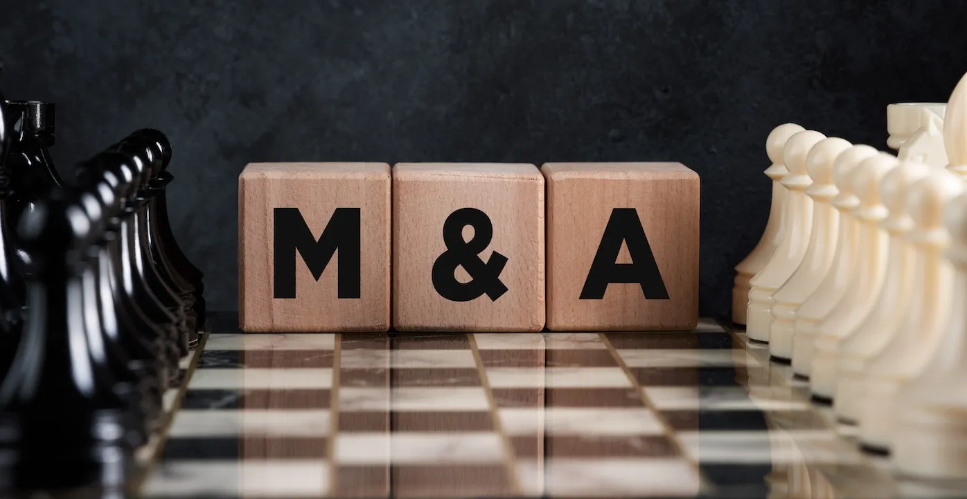 M&A Chessboard with chess pieces and wooden blocks with the word mergers and acquisitions