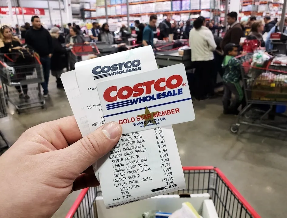Costco Wholesale card and receipt in hand in busy store