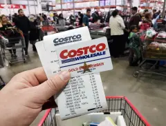 Costco Wholesale card and receipt in hand in busy store