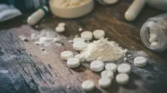 Opioid pills on a wooden table.