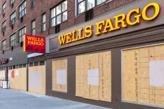 Wells Fargo windows boarded up with plywood on empty street