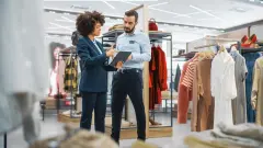 Clothing Store: Businesswoman Uses Tablet Computer, Talks to Visual Merchandising Specialist, Collaborate To Create Stylish Collection. Small Business Fashion Shop Sales Manager Talks to Designer.