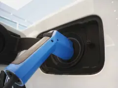 Blue electric vehicle charger plugged into white car