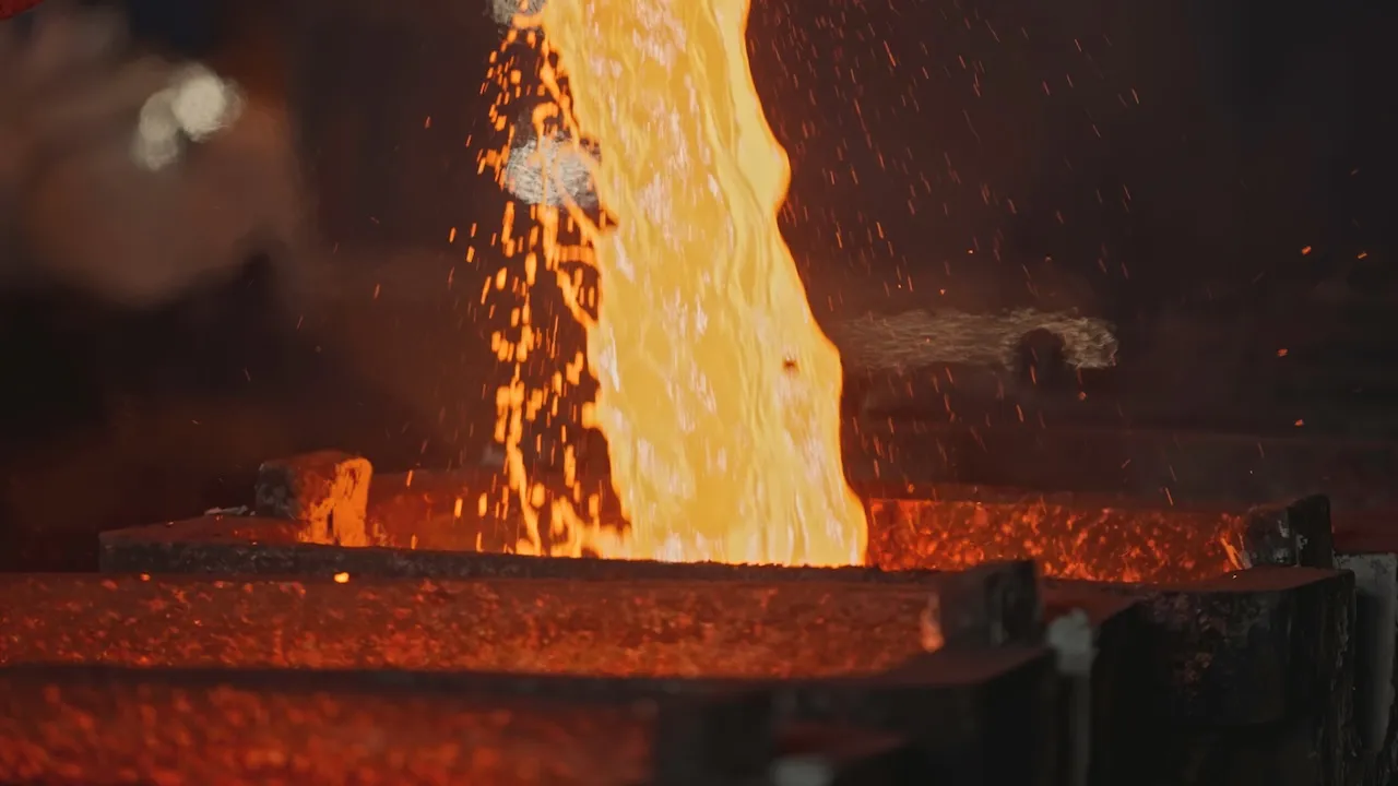 Pit pours liquid metal into molds. Stock footage. Liquid mass of molten metal pours out of pit. Stream of liquid metal is poured into molds at metallurgical 
