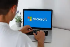 Man typing on Laptop with Microsoft Logo on screen