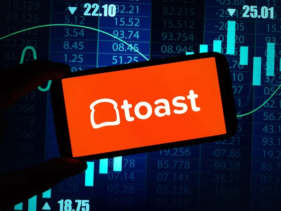 Toast Inc logo on smartphone, tech background behind.
