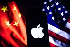 A stark Apple logo on a phone screen with the contrasting flags of China and the U.S. as a backdrop, representing the tech interplay between the two nations.