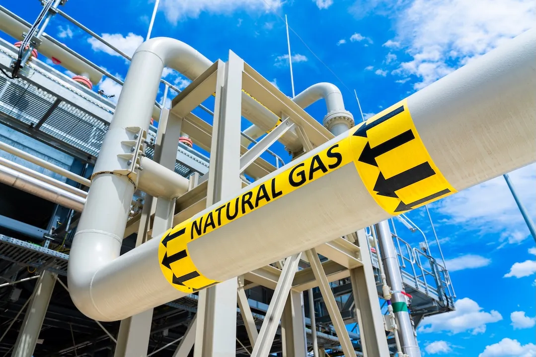 Natural gas pipeline with high pressure and direction sign at compressor station. Concept of energy transportation infrastructure