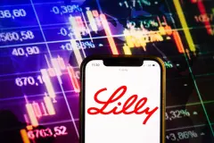 Lilly Logo on Smartphone with stock charts in background