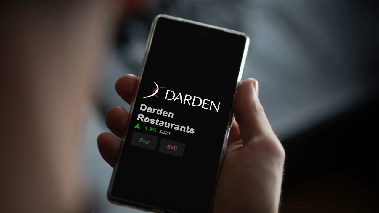 The logo of Darden Restaurants on the screen of an exchange. Darden Restaurants price stocks, $DRI on a device.