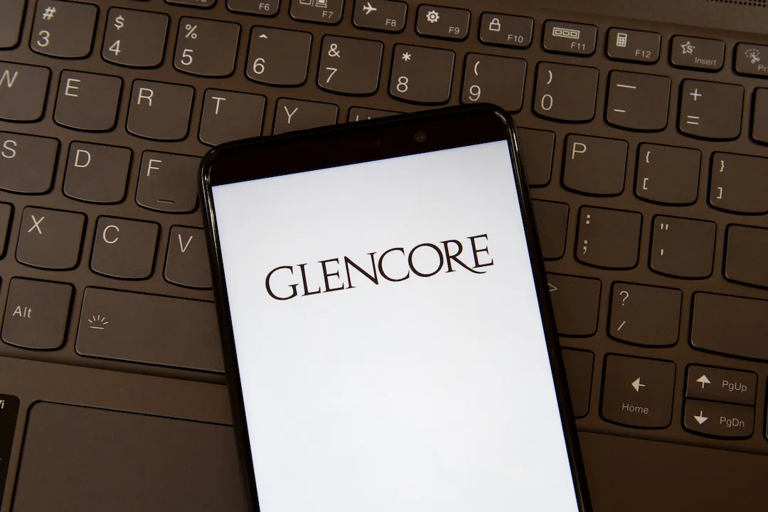Glencore Logo on Smartphone screen against keyboard background.